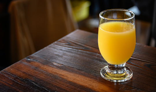 Glass cup of orange juice and a wooden reamer. Selective focus