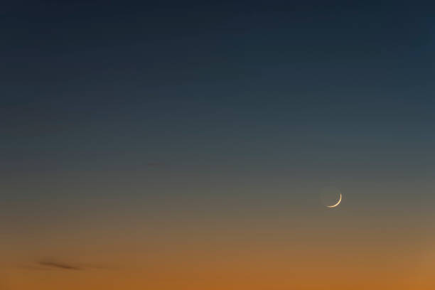 Wonderful sunset sky with orange and blue tones with waxing crescent moon.