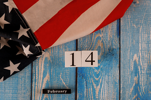 14 February calendar beautifully waving star and striped American flag on old blue wooden board.