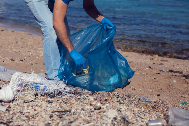 istock Man volunteer with big bag for trash collecting garbage on beach. Environmental pollution concept 1196275432