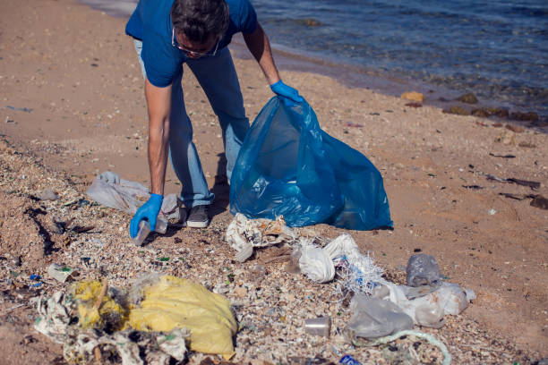 istock Man volunteer with big bag for trash collecting garbage on beach. Environmental pollution concept 1196275447