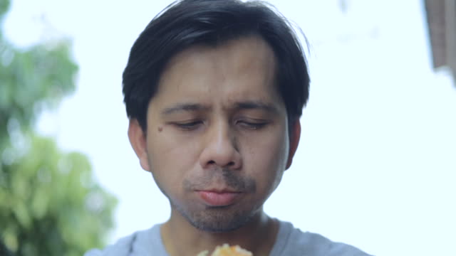 Close up young asian man eating hamburger