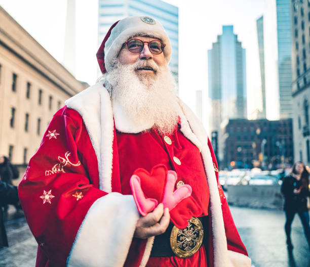Santa Clause on downtown street in big North American city. Long white beard, Red suit, boots and all. Ready for Christmas.