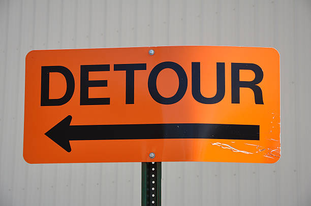 A beat up orange detour sign on a city street