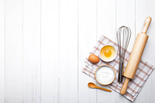 istock Bakery ingredients. wheat ears and bowl of flour,egg,rolling pin,egg whisk  on white background,Homemade bread, top view 1196296819