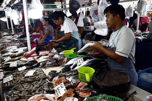 Antipolo City, Philippines – December 23, 2019: Vendors at a public wet market sell fish and other seafood to customers.