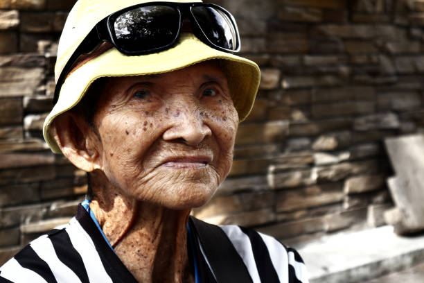 Antipolo City, Philippines – December 21, 2019: Senior Filipino man sit on a sidewalk and pose for the camera.