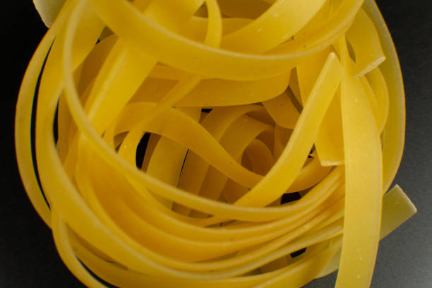raw italian tagliatelle Pasta on dark background