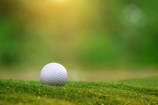 мяч для гольфа находится на зеленой лужайке в красивом поле для гольфа - golf golf flag sunset flag стоковые фото и изображения