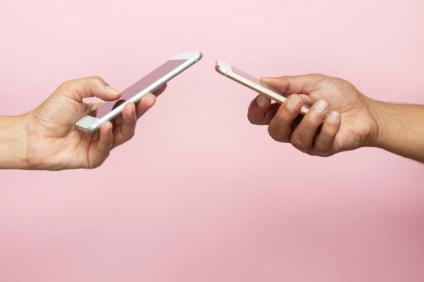 istock Two Hands Holding Mobile Phones 1196316392