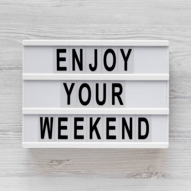 istock 'Enjoy your weekend' words on a modern board on a white wooden surface, top view. Overhead, from above, flat lay. Close-up. 1196318049