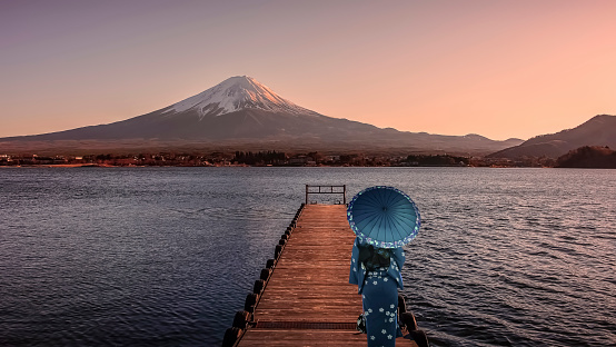 Girl with traditional dress look at Mount Fuji from Kawaguchi lake in evening