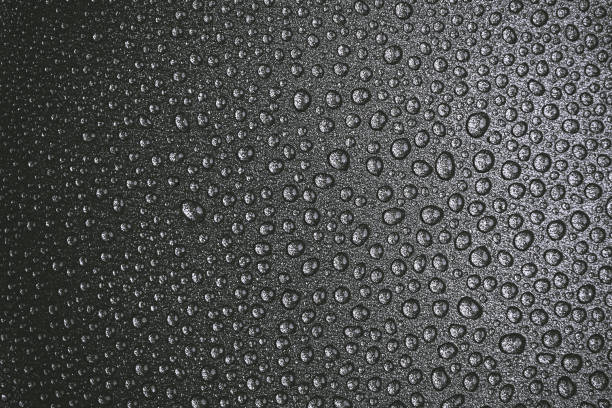 istock many drops of water on a dark surface - non-stick coating in a pan. Center in sharpness, blurred edges. Black and white photo 1196330211