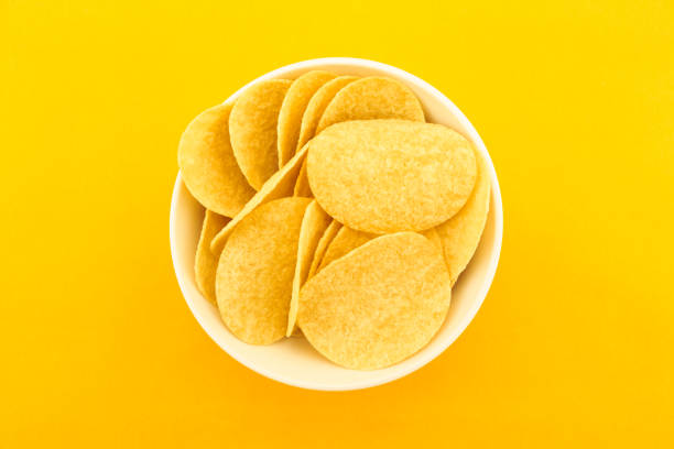 istock potato chips on bowl on yellow background. 1196333916