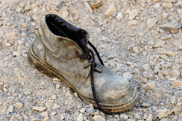 istock Old pair of shoes on sand 1196336576