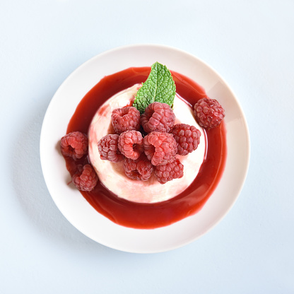 Panna cotta with fresh raspberries in bowl on blue stone background. Tasty healthy dessert. Top view, flat lay