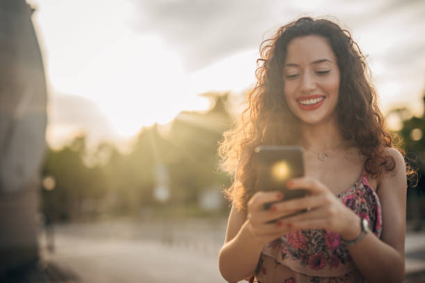 istock Beautiful young woman using mobile outdoors 1196338524