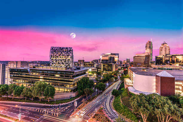 sandton stadt bei nacht mit mond am himmel - johannesburg night skyline dusk stock-fotos und bilder