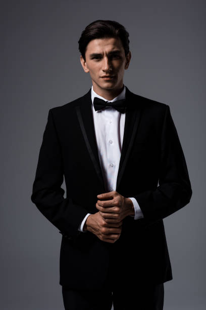 istock handsome young man in suit and bow tie, isolated on grey 1196349258