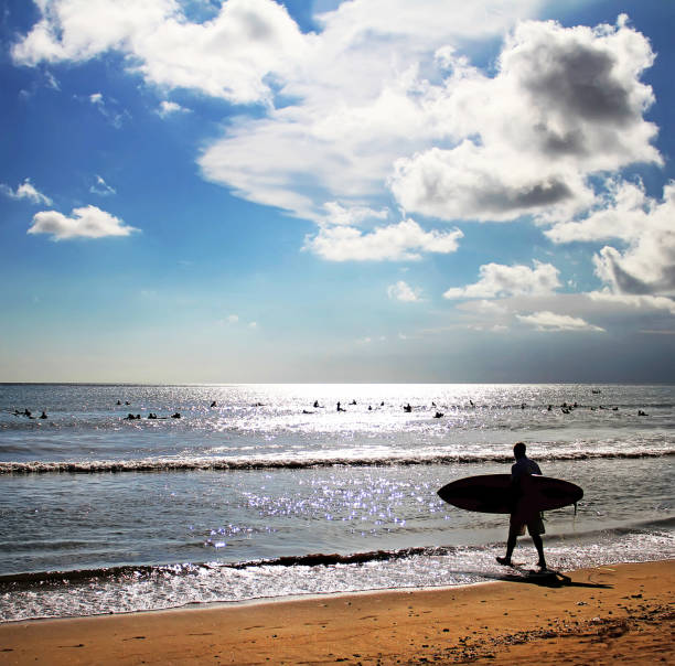 Bali, Indonesia - 18th September 2010. A young adult surfer prepares to enter the sea at Kuta beach in Bali.