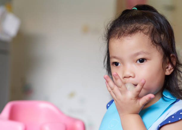 istock Cute little children eating fruit by hand at home. 1196350141