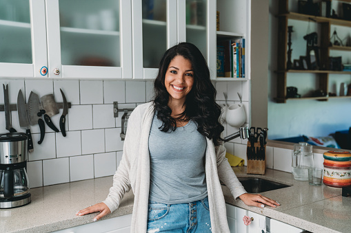 Portrait of a young adult woman in the kitchen. Hispanic ethnicity.