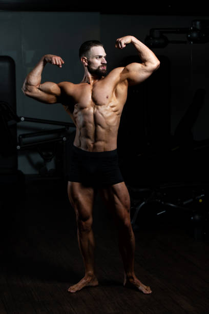 istock Muscular Man Is Hitting Rear Double Bicep Pose 1196354097