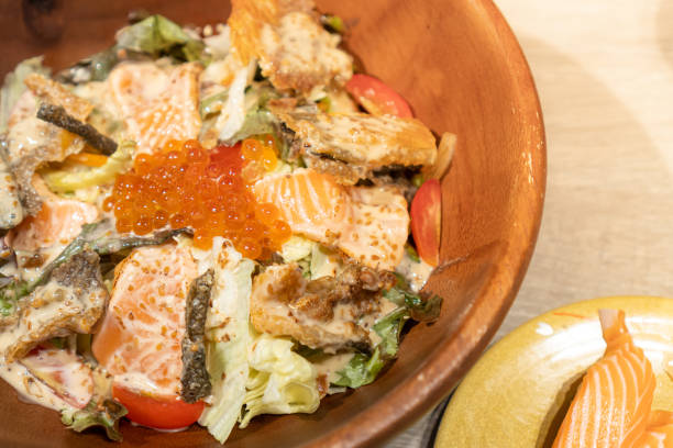 la salade de saumon se compose de divers légumes, saumon frais, peau de saumon et œufs servis dans un bol en bois - gourmet salad dinner prepared fish photos et images de collection