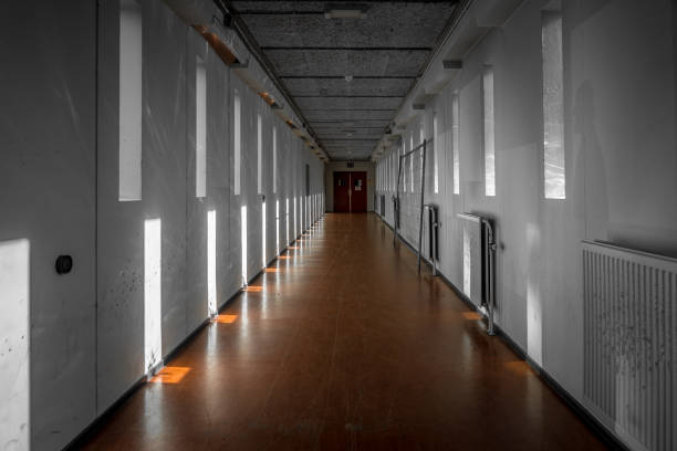 A long bare corridor with light and dark shadow spots. The corridor evokes an unpleasant and anxious feeling