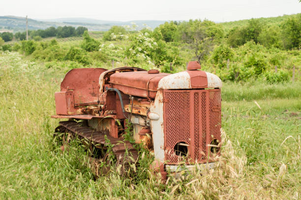 Old neglected rusty small vintage caterpillar tractor on green meadow