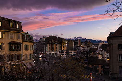 A street of Lausanne overlooked by the mountains of the Alps during sunset.