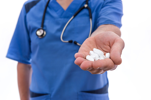 doctor in blue uniform gives pills isolated on white background