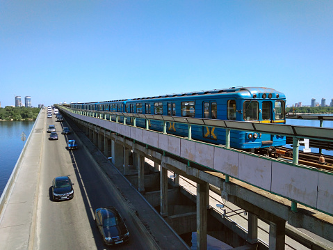 Kyiv, Ukraine - May 30, 2018: Dnipro is a station on the Kiev Metro's Sviatoshynsko-Brovarska Line. The train crosses the bridge over the Dnieper River in Kiev. Cars are moving on the highway.
