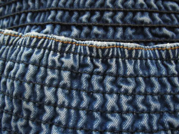 Photo of Large elastic waistband in jeans. Denim texture. Blue jeans background. Close-up. Copy space.