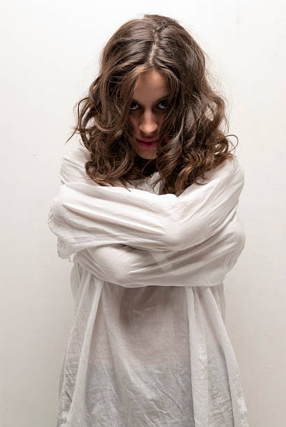 Young insane woman with straitjacket standing looking at camera stock photo