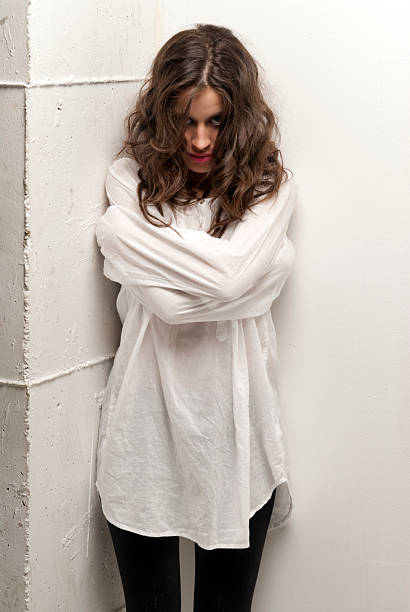 Young insane woman with straitjacket standing looking at camera stock photo