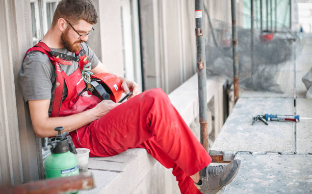istock Building site worker on the scaffolding using mobile phone 1196372512