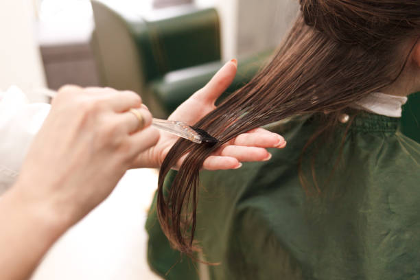 парикмахер наносит маску для волос женщине в салоне красоты. процедура выпрямления волос ботокса и кератина - beauty treatment стоковые фото и изображения