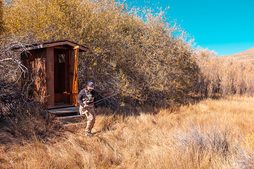 Rosaschi Ranch, East Walker River, Nevada.Fly Fisherman Using The Outhouse at Rosaschi Ranch, East Walker River, Nevada.