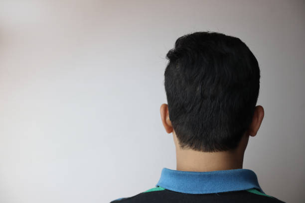 灰色に隔離されたテキストのためのコピースペースを持つ若いインドの男性の頭の後ろ。 - shaved head ストックフォトと画像
