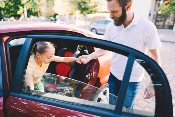Father helping daughter to leave the car Father takes his daughter to school with car disembarking stock pictures, royalty-free photos & images