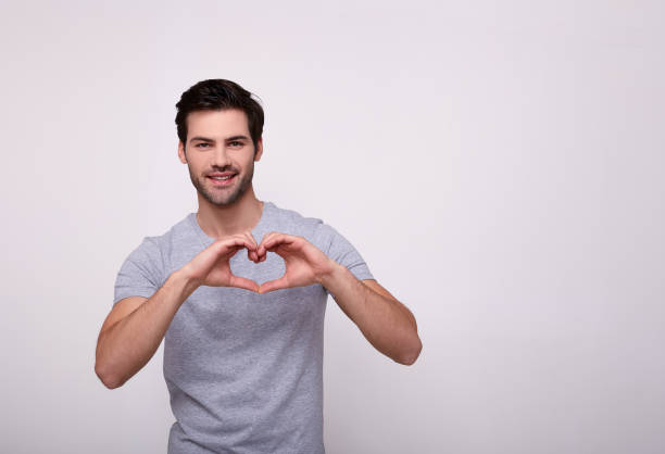 istock Smiling charming guy with his hands heart on a white background. 1196384449