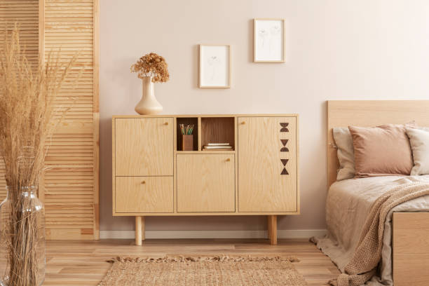 istock Flowers in vase on wooden commode in simple bedroom interior 1196385675