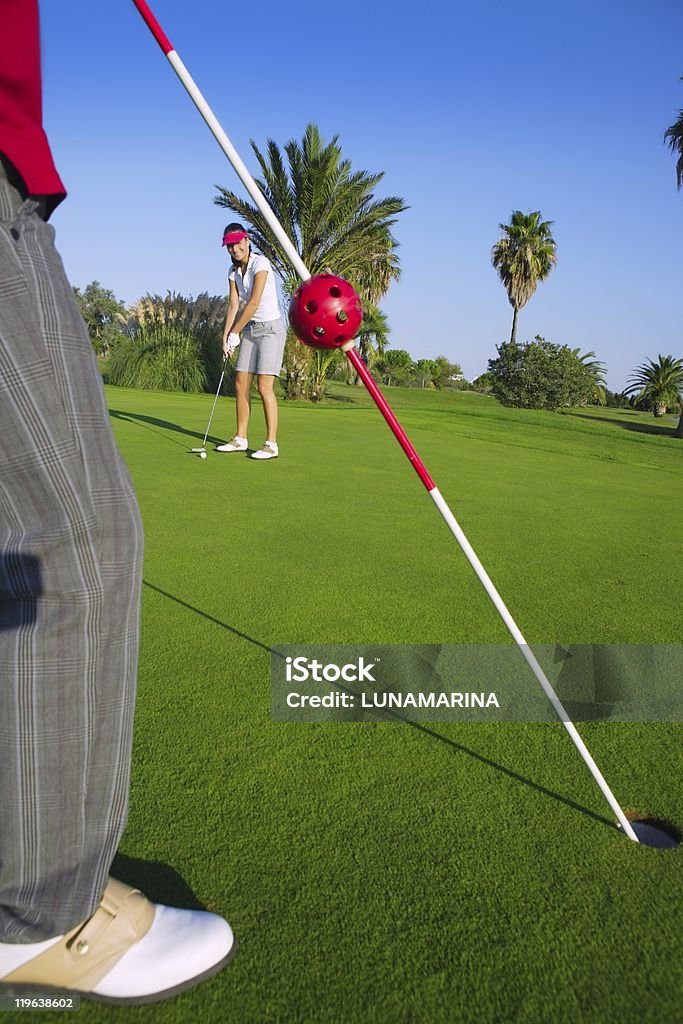 golf woman putting gol ball and man holds flag  Adult Stock Photo