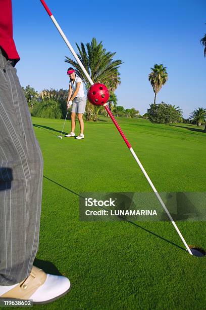 Golf Woman Putting Gol Ball And Man Holds Flag Stock Photo - Download Image Now - Adult, Aiming, Beautiful People