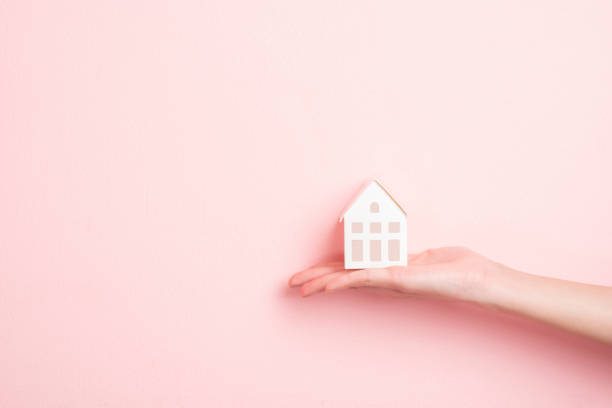 istock Small white house on human hand 1196389400