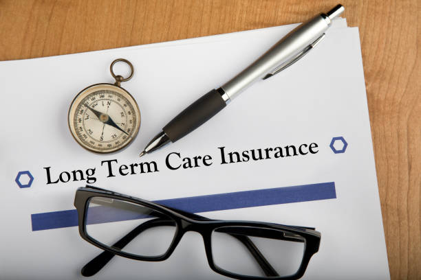 Long Term Health Insurance document on desk, with compass, glasses, and pen Documents on table for the premise of calculating the amount and direction needed for Long Term Health Care. Navigating Customer Service and Claims Handling stock pictures, royalty-free photos & images