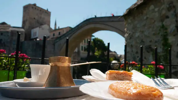 Coffee and Turkish sweets on the table with the view of Old bridge - Mostar, Bosnia and Herzegovina.