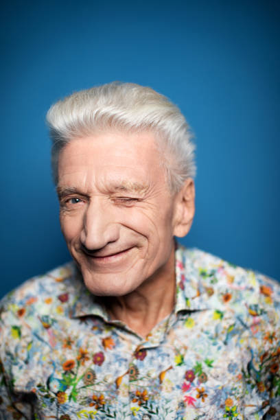 istock Happy senior man winking against blue background 1196391514