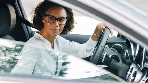 Young female entrepreneur driving a car looking away Young female entrepreneur driving a car looking away carsharing photos stock pictures, royalty-free photos & images